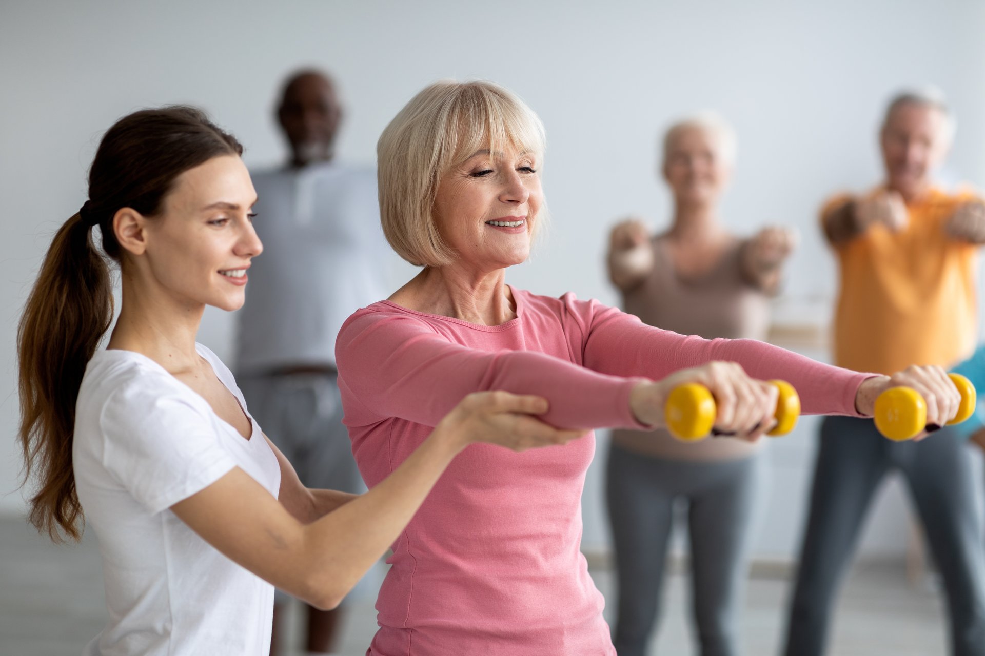 Trainerin begleitet Patientin beim Hanteltraining
